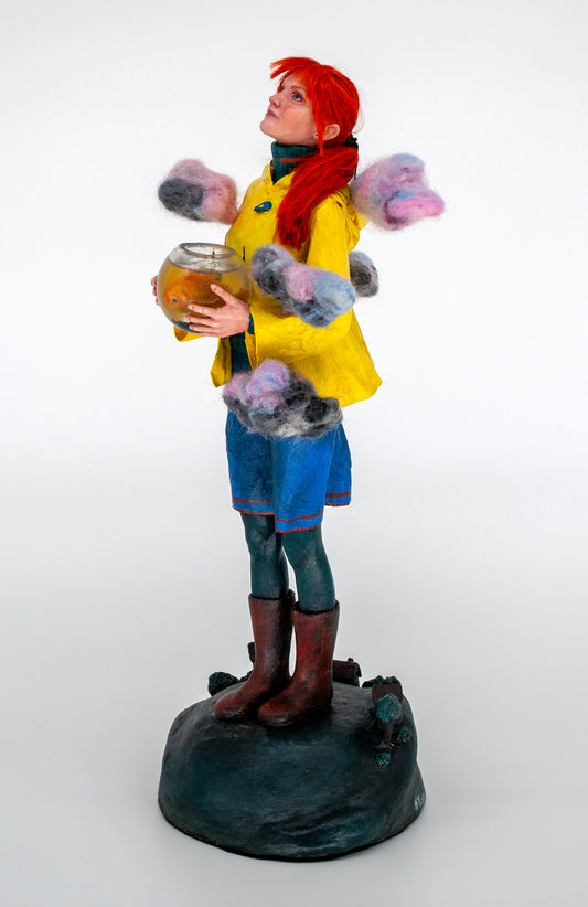 Realistic sculpture of a girl with red hair wearing a yellow raincoat holding a fishbowl above the world