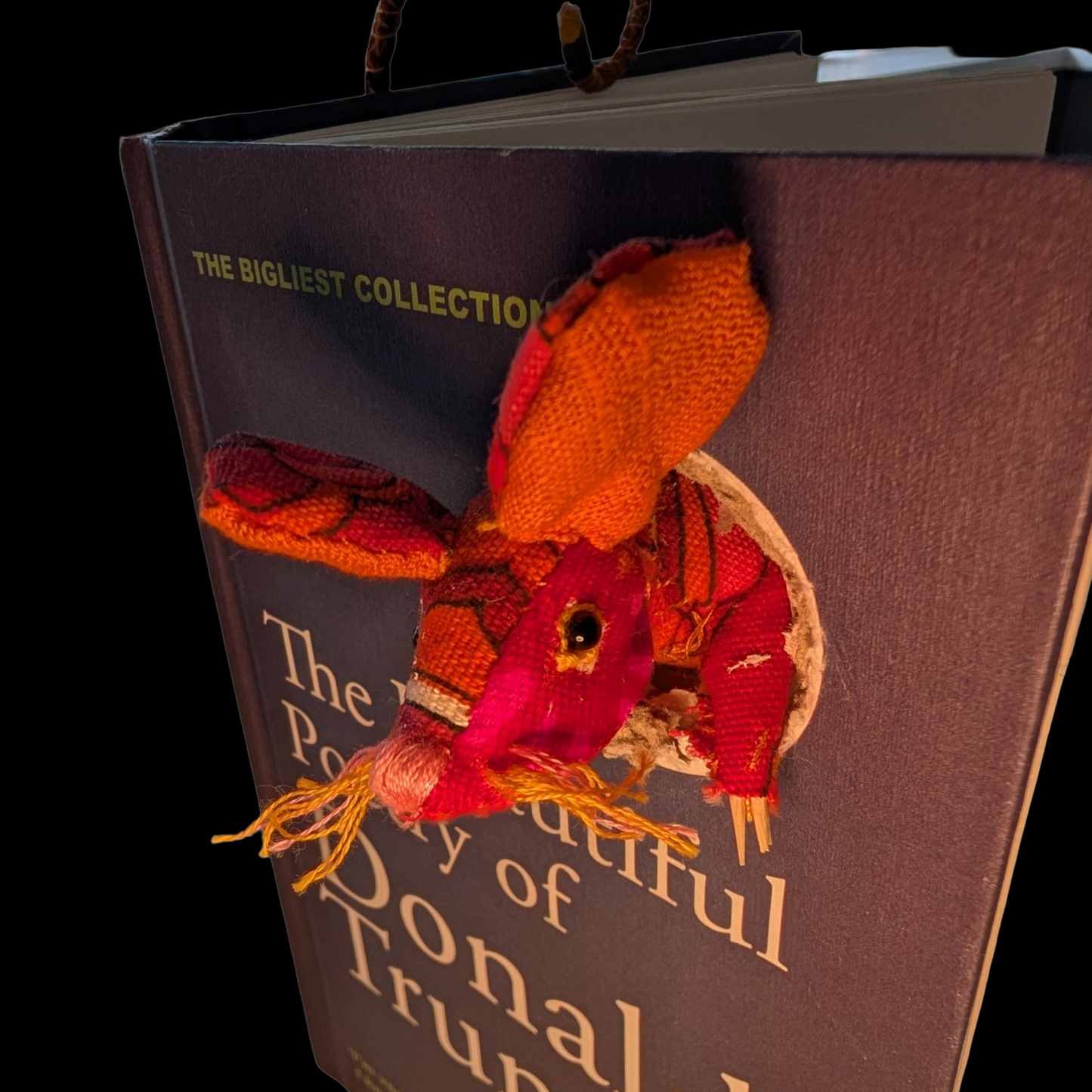 Textile taxidermy rodent destroying a satirical book of poetry by Donald Trump
