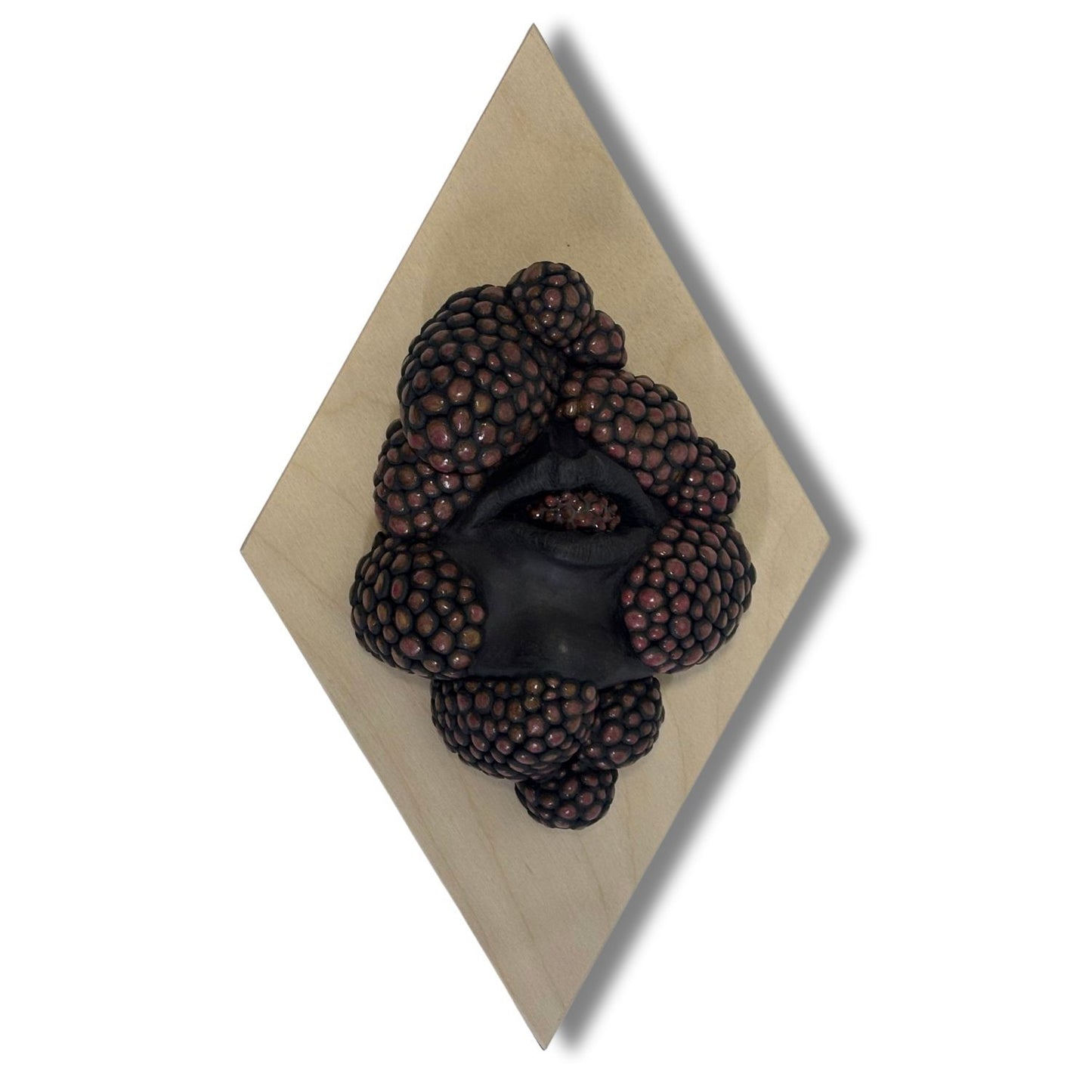Surrealist black stoneware clay wall hanging combining facial features and berries
