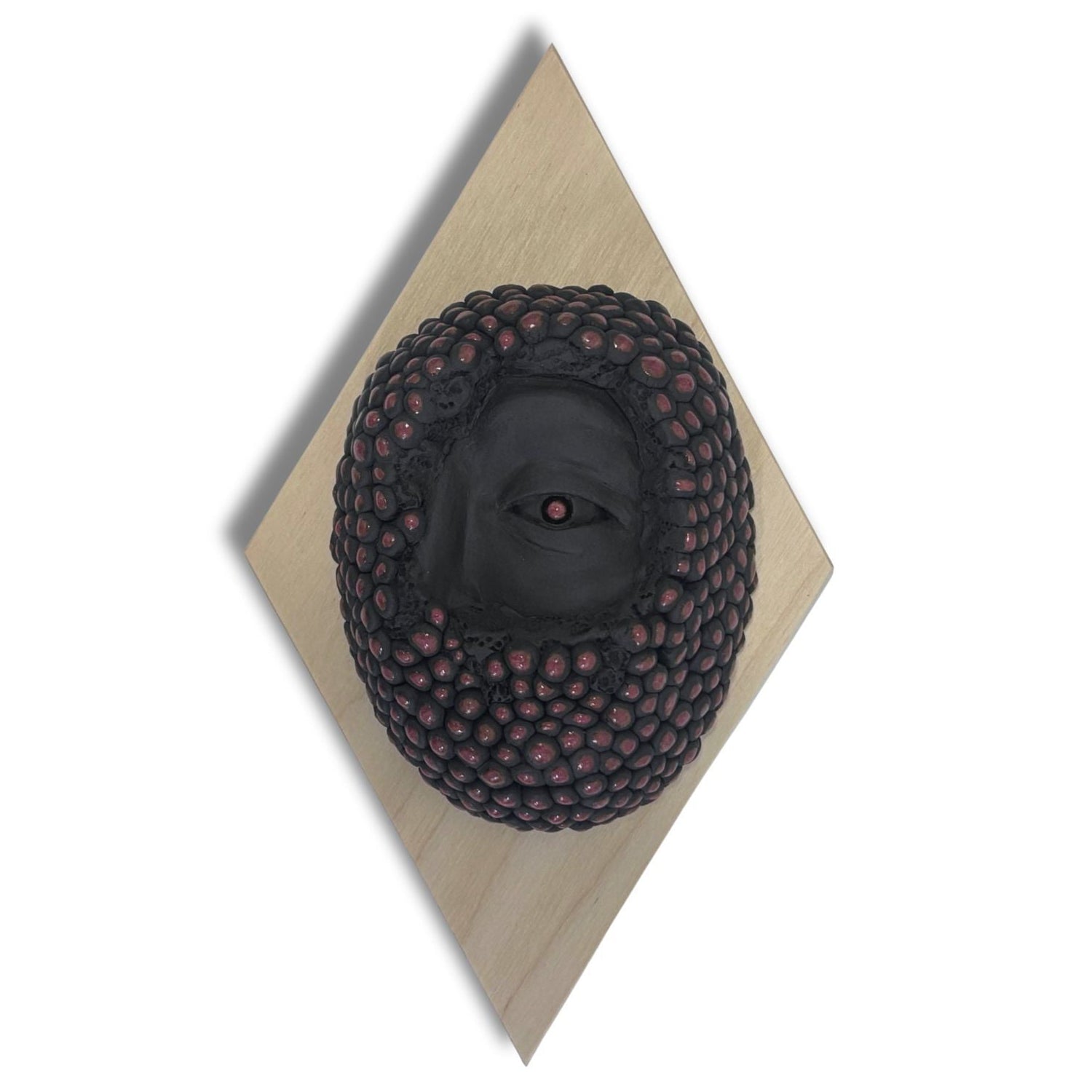 Surrealist black stoneware clay wall hanging combining facial features and berries