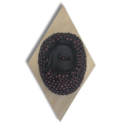 Surrealist black stoneware clay wall hanging combining facial features and berries