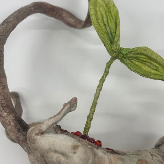 Close up of fabric taxidermy rat with a plant emerging from its stomach