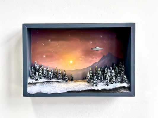 Art diorama featuring a UFO over snowy trees at sunset