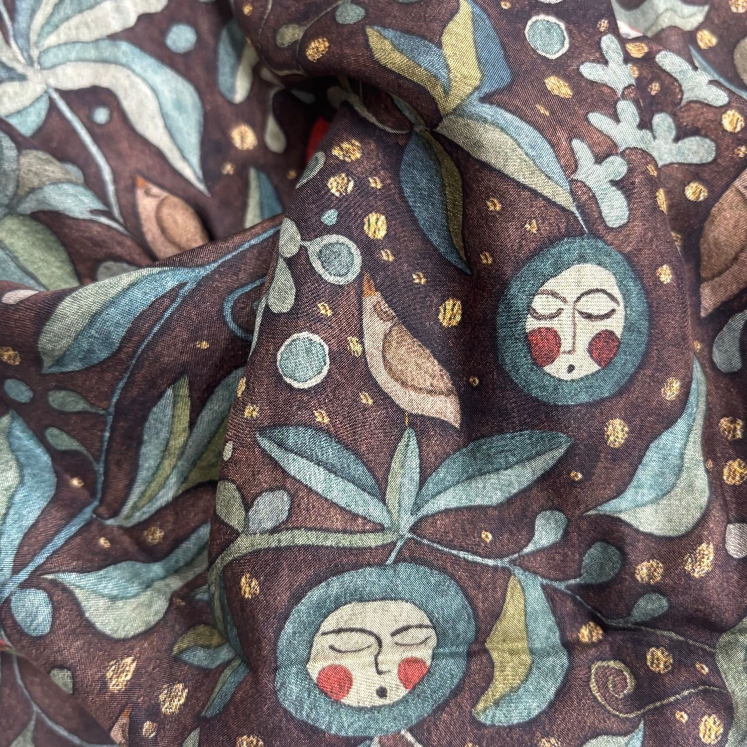 Close-up of fabric with decorative pattern featuring faces, leaves, and birds.