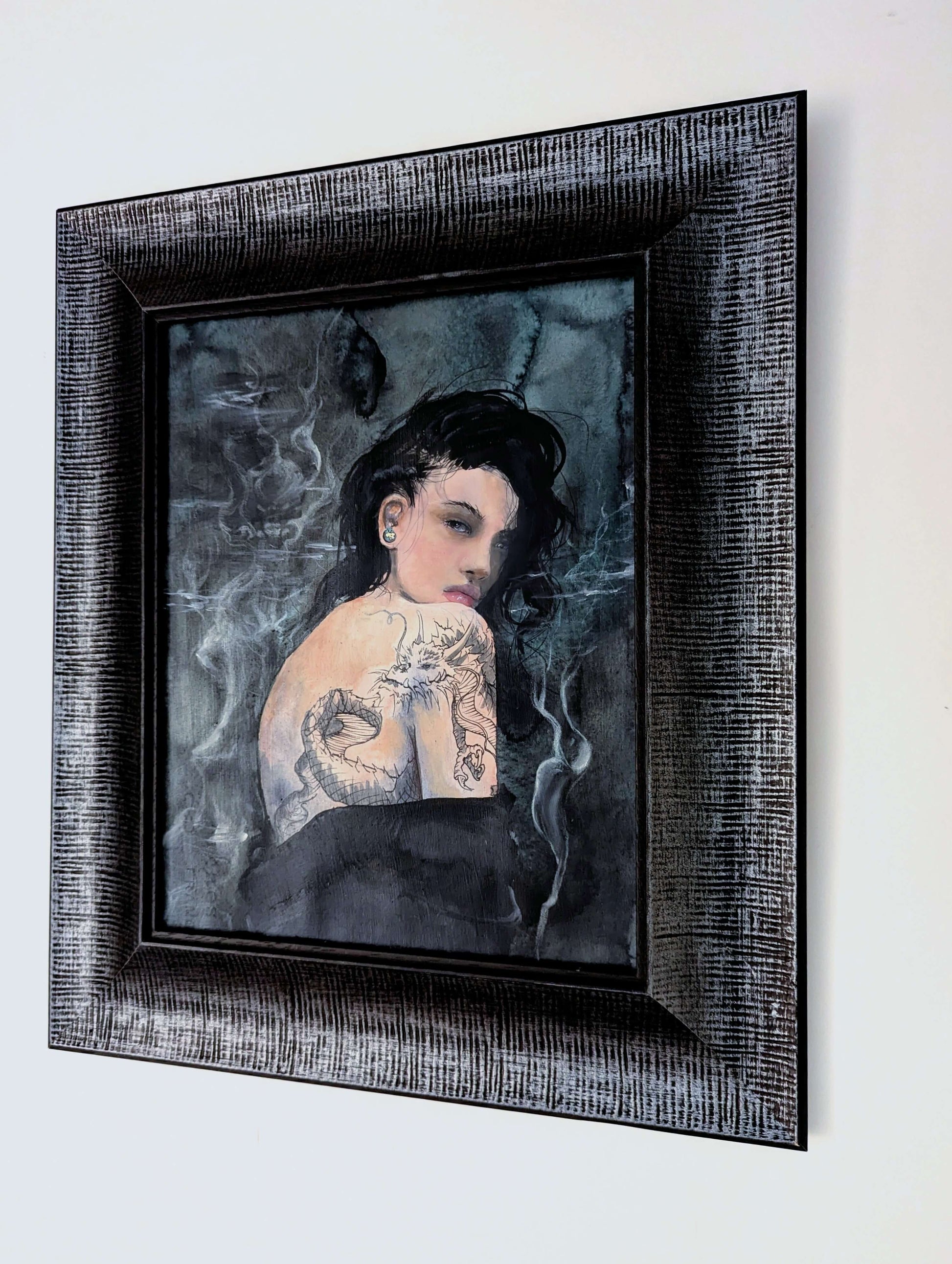 Framed artwork of a woman with tattoos on a light gray background