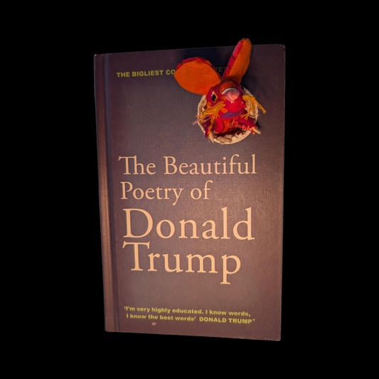 Textile taxidermy rodent destroying a satirical book of poetry by Donald Trump