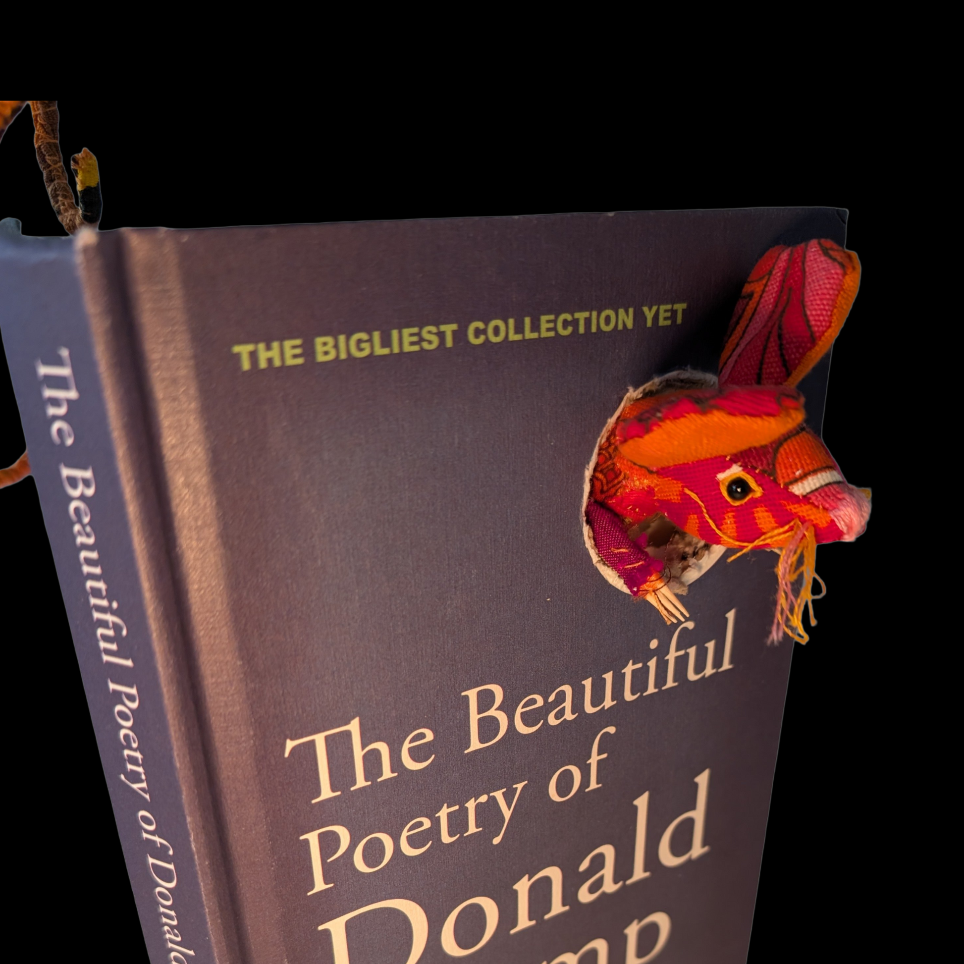 Textile taxidermy rodent destroying a satirical book of poetry by Donald Trump