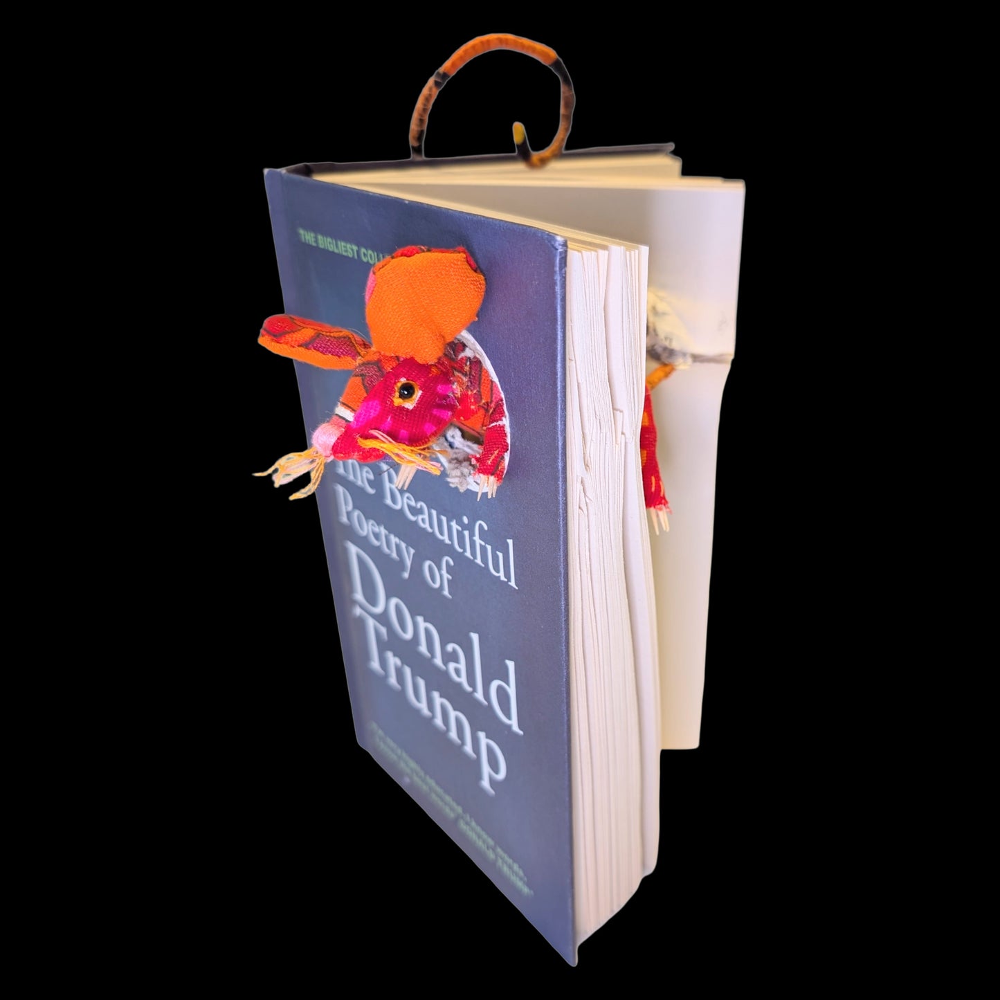 Textile taxidermy rodent destroying a satirical book of poetry by Donald Trump