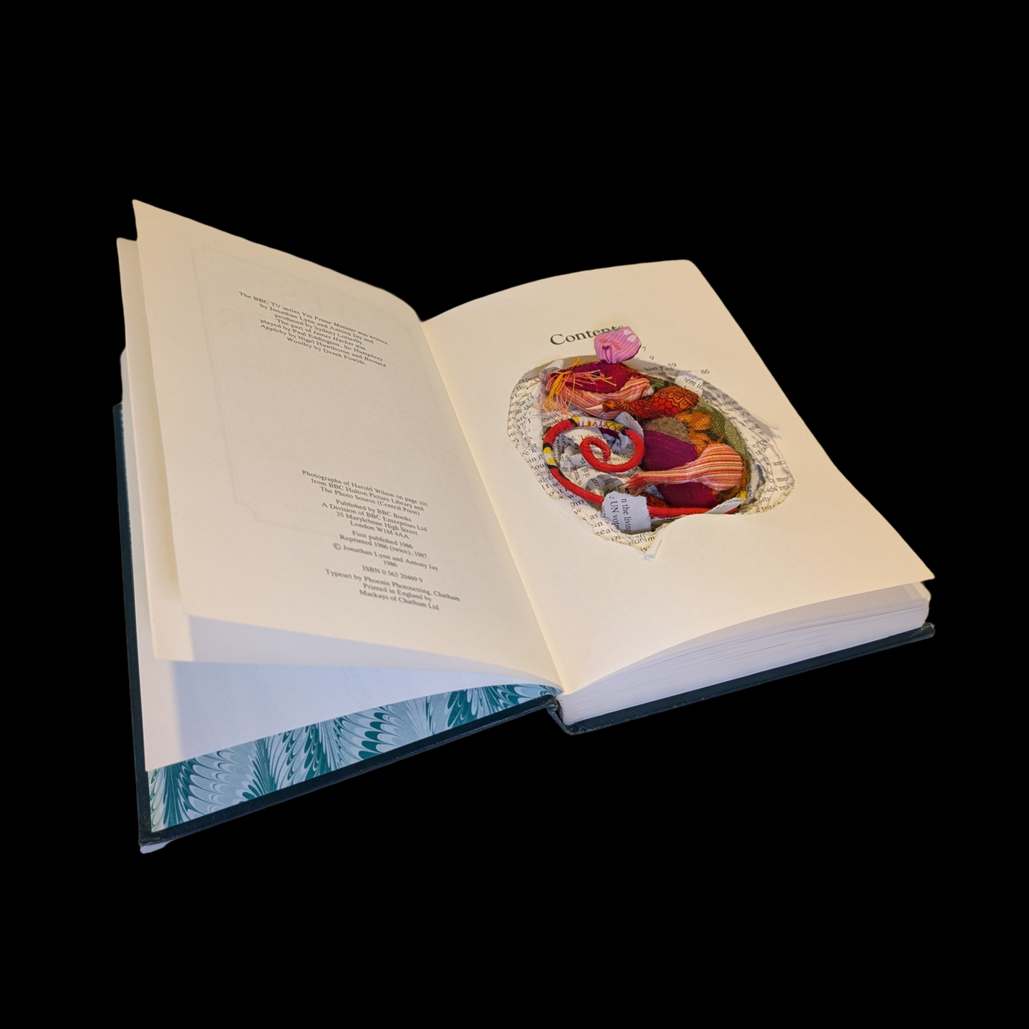 Textile taxidermy rodent nestled down in a book 