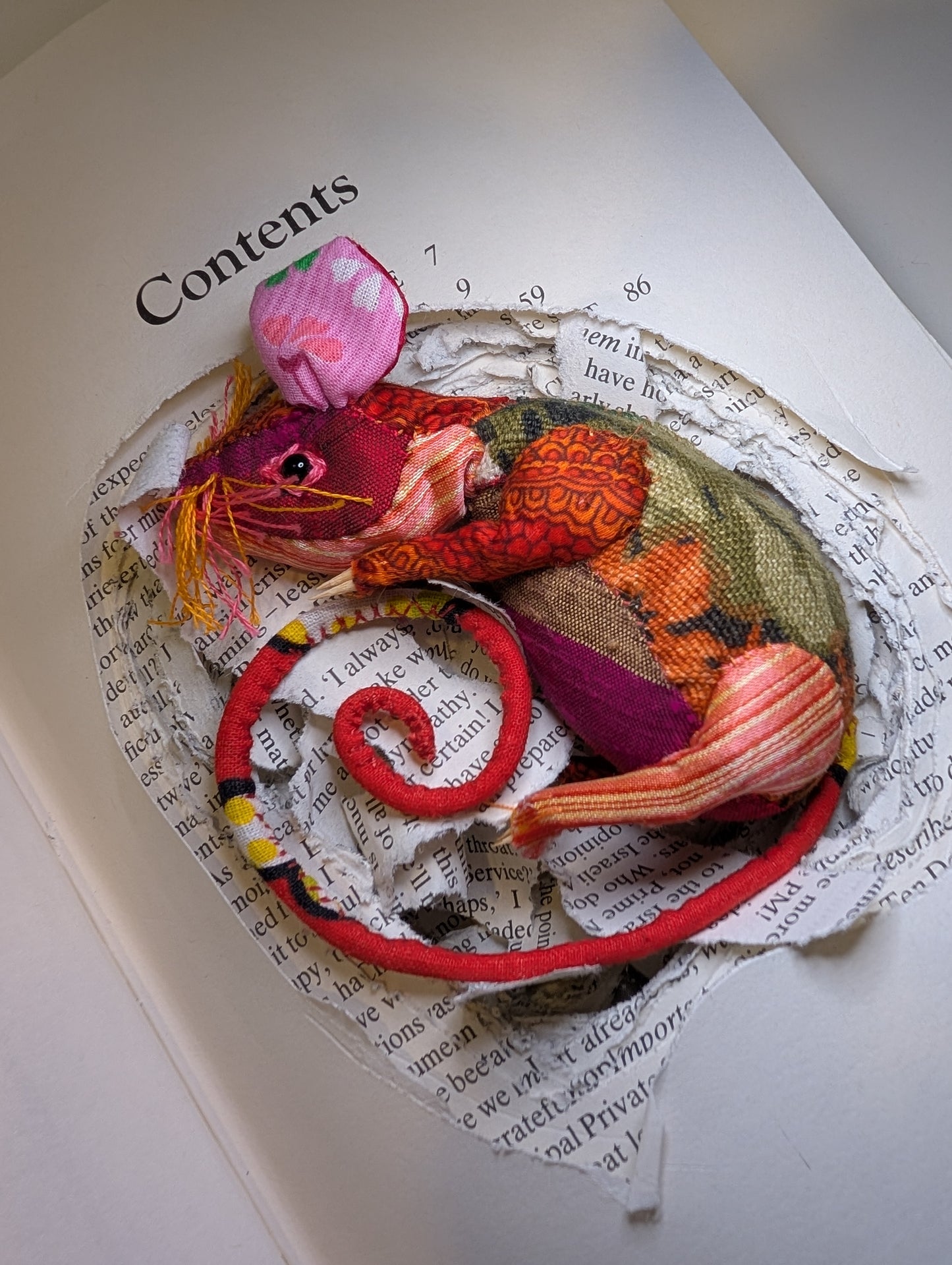 Textile taxidermy rodent nestled down in a book 