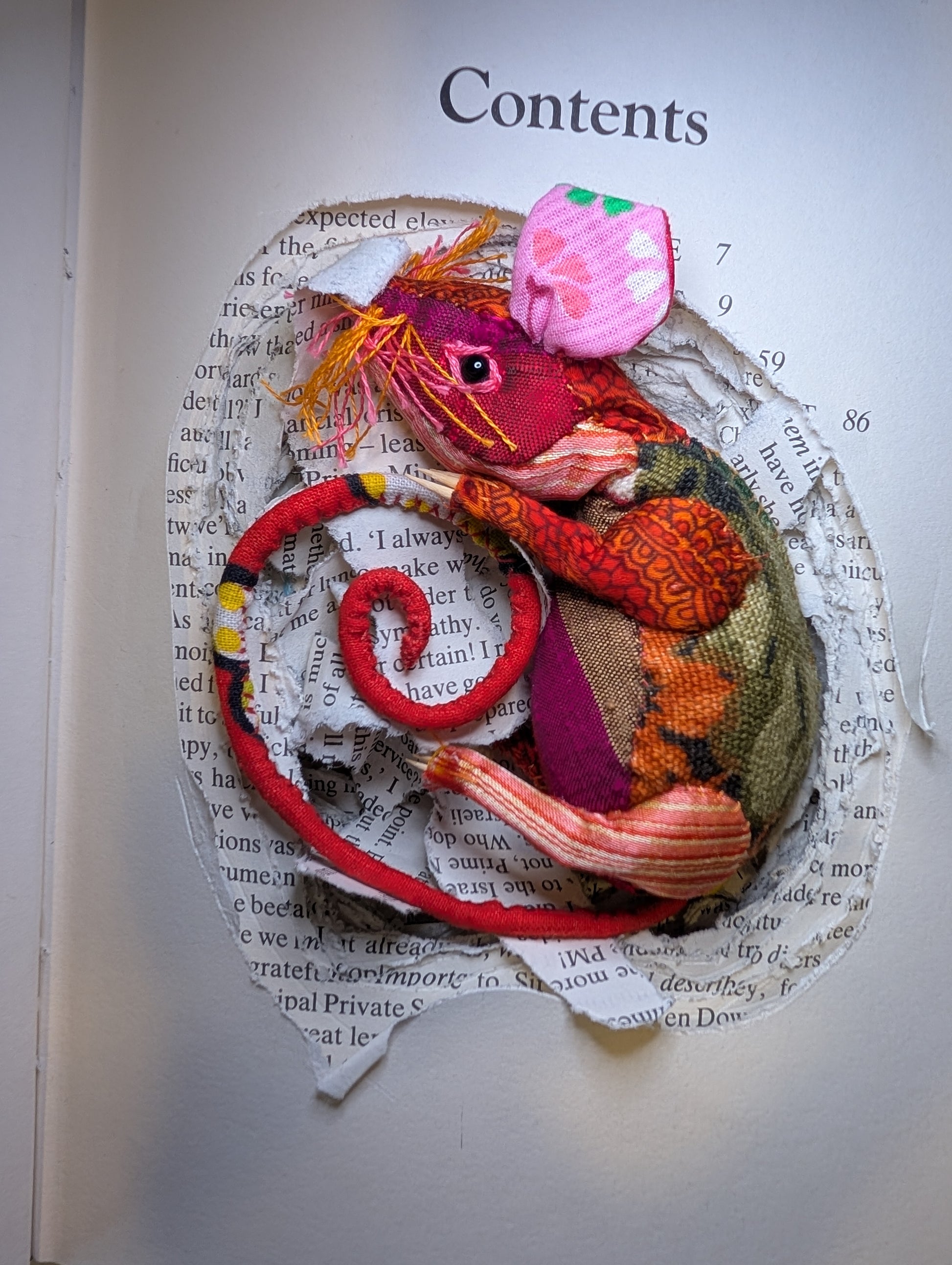 Textile taxidermy rodent nestled down in a book 