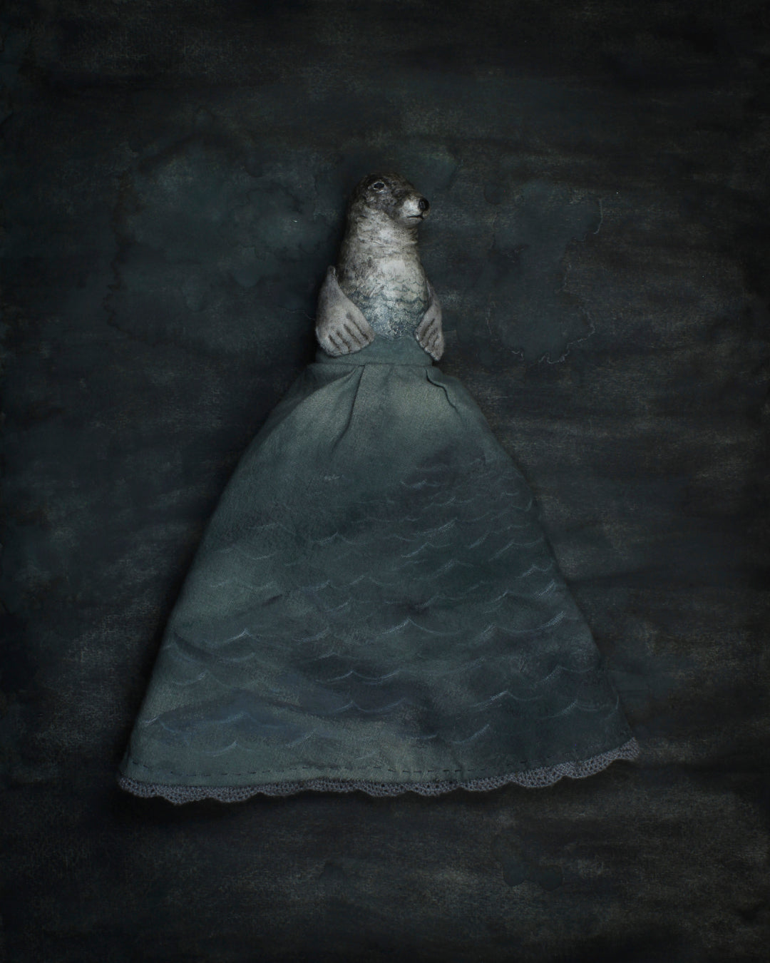 A seal dressed in a long, voluminous dark teal-blue gown, one of a two reversible figures in ‘Selkie’ by Anne Breymann