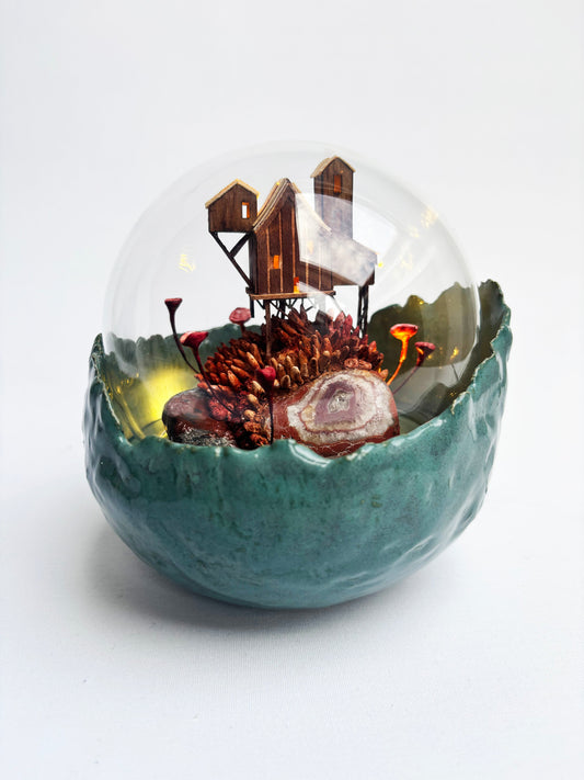Glass sphere with miniature landscape inside on a white background