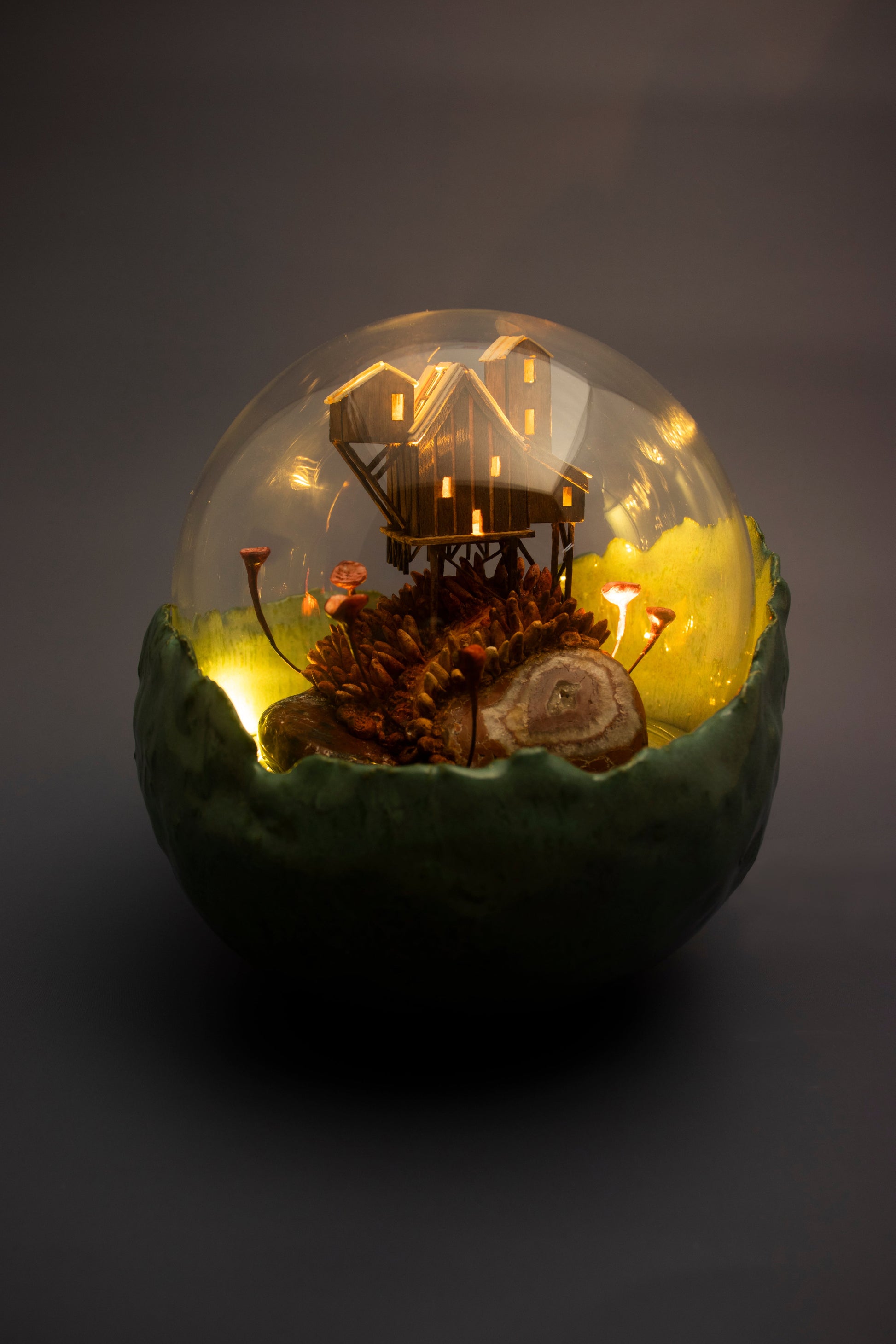 Decorative glass sphere with miniature landscape and lights on a dark background