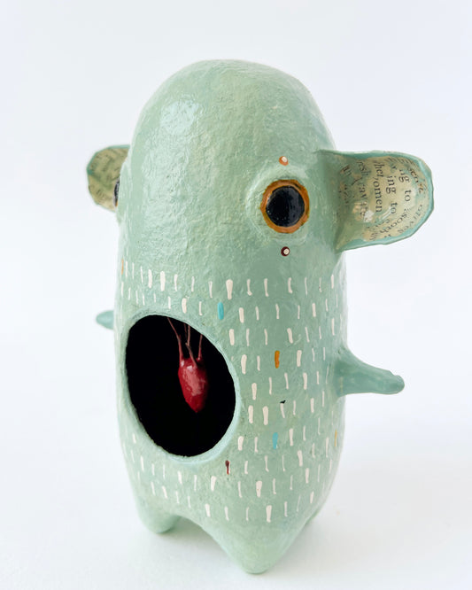 Green paper mache creature with exposed heart