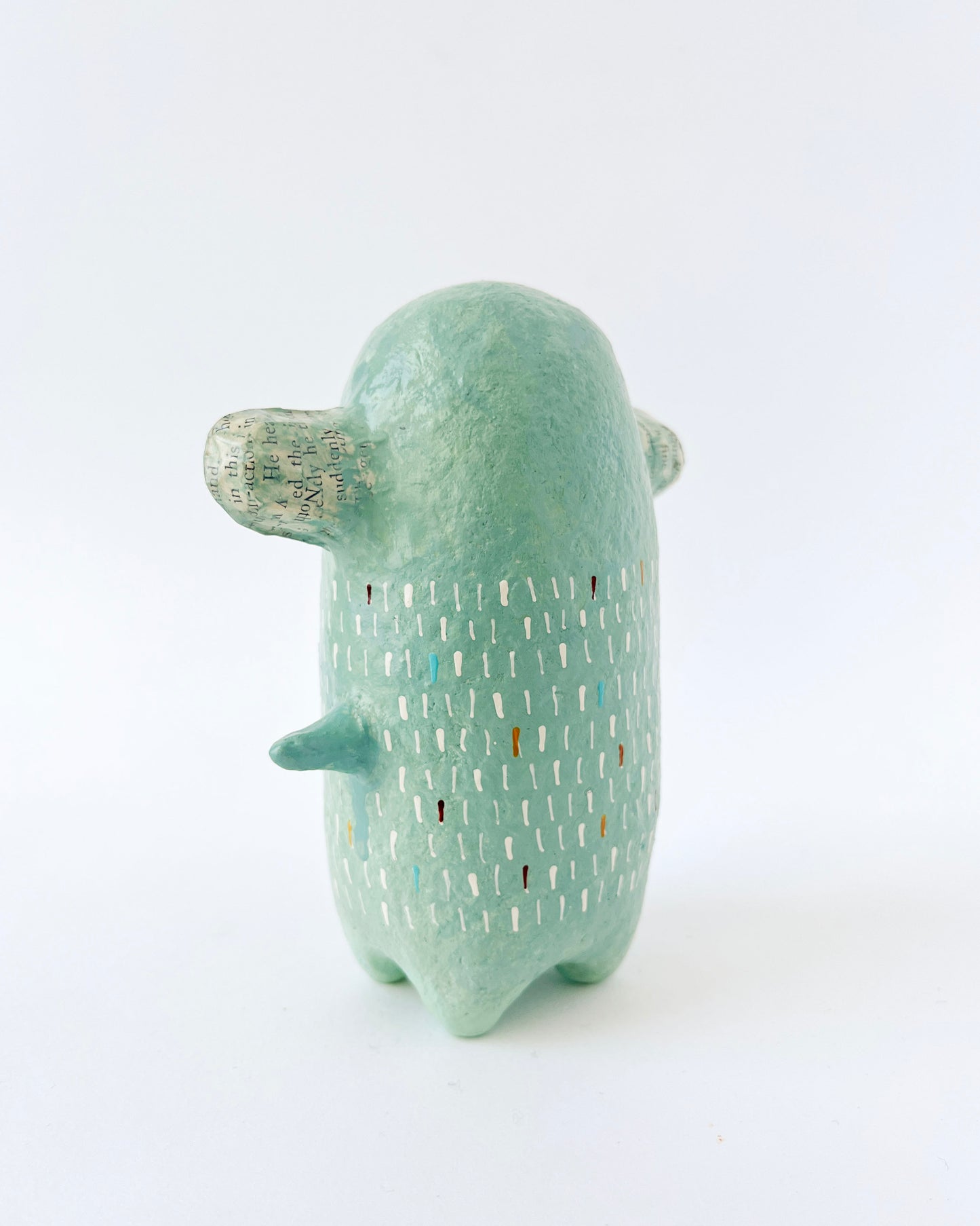 Green paper mache creature with exposed heart