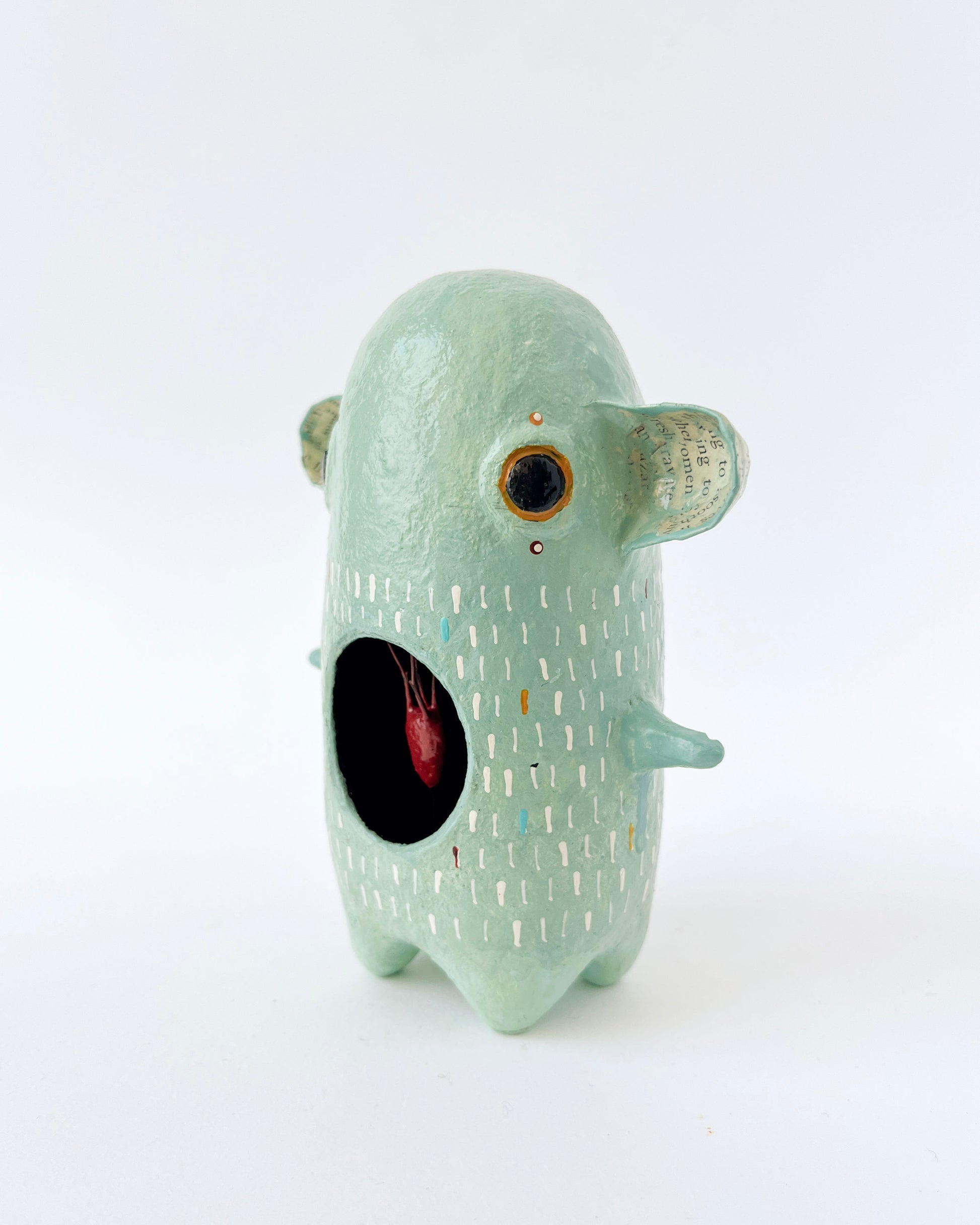 Green paper mache creature with exposed heart