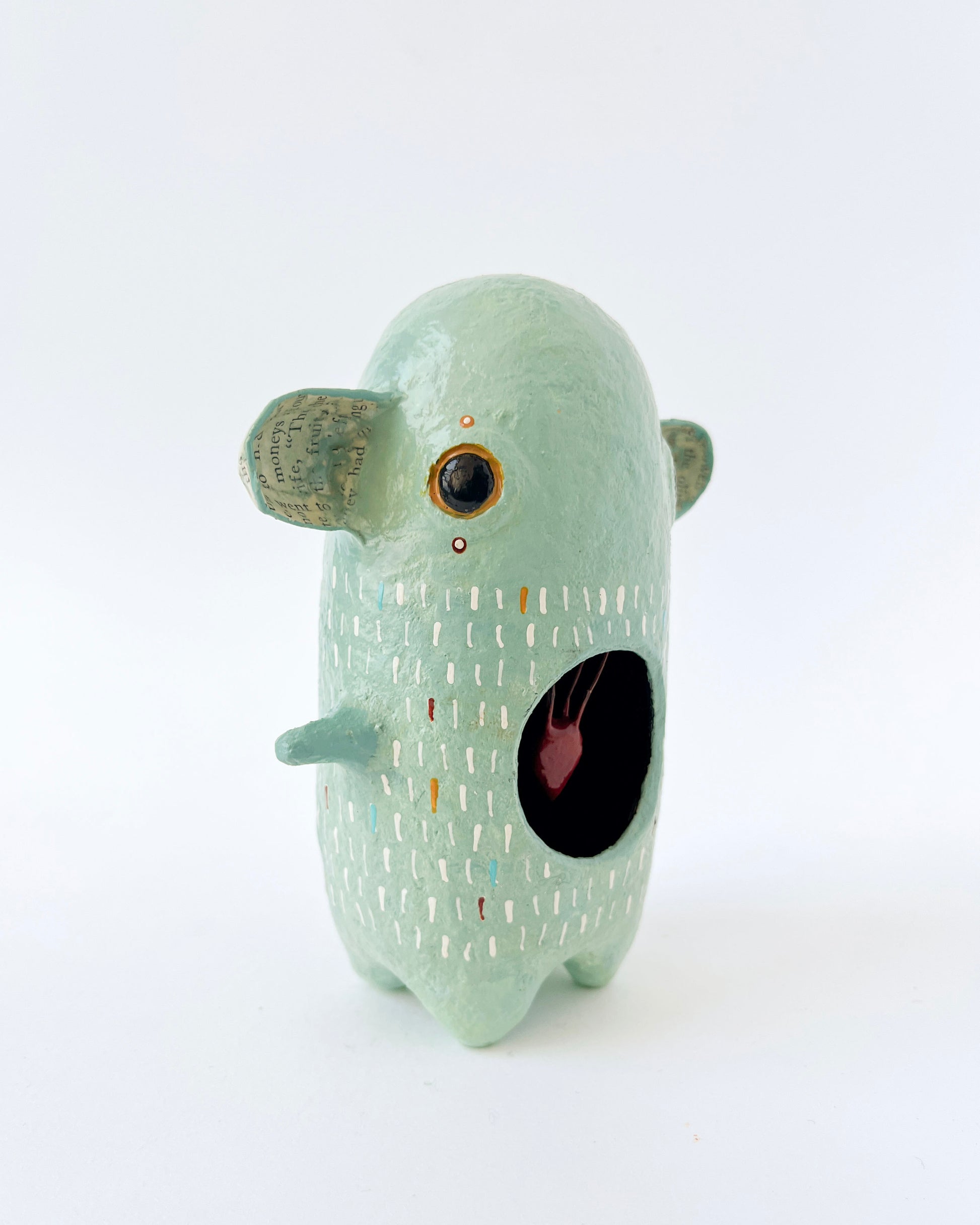 Green paper mache creature with exposed heart